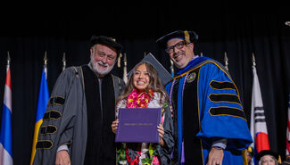 Student smiling while getting her photo taken with the LLU President and Dean of the School of Nursing
