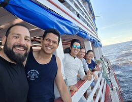 A group of five mission trip volunteers consisting of students, alumni and administration smile and stand on the side of a boat traveling the Amazong River in Brazil.