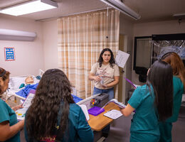A nursing leader trains a team of nurses in a simulation environment.