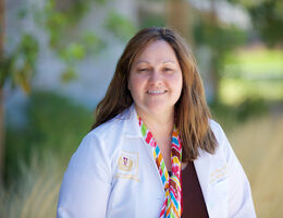 Dr. Joanna Shedd stands and smiles in her whitecoat 